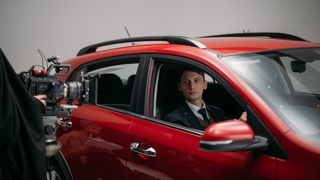 Professional male actor works in the frame on the set. Shooting with a car